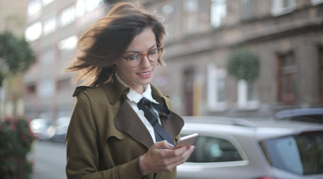 stylish adult female using smartphone on street